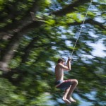 Boys jumping from a rope swing at Lake Bled, Slovenia